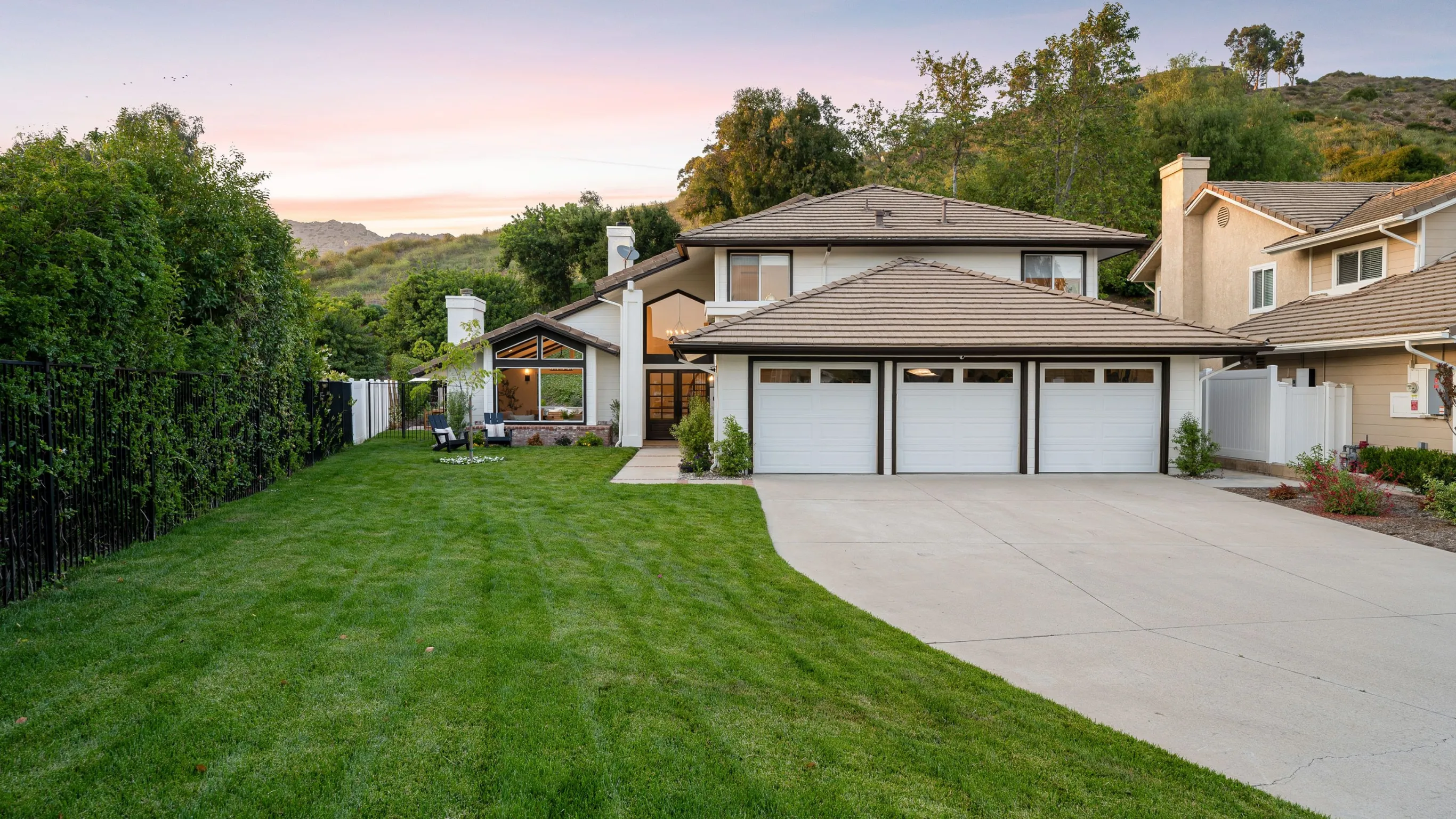 Before photo of garage conversion ADU project in Los Angeles with attached garage doors, wide driveway, lawn area, hillside backdrop, and original garage structure before conversion