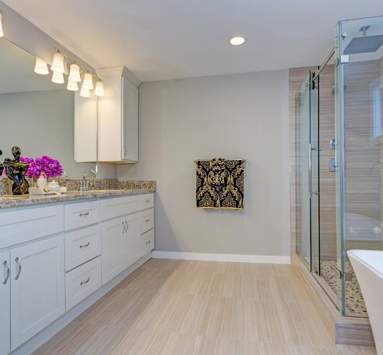 Bathroom remodeling in Los Angeles with glass shower enclosure, white vanity cabinets, stone countertop, updated lighting, tile flooring, and modern bath design