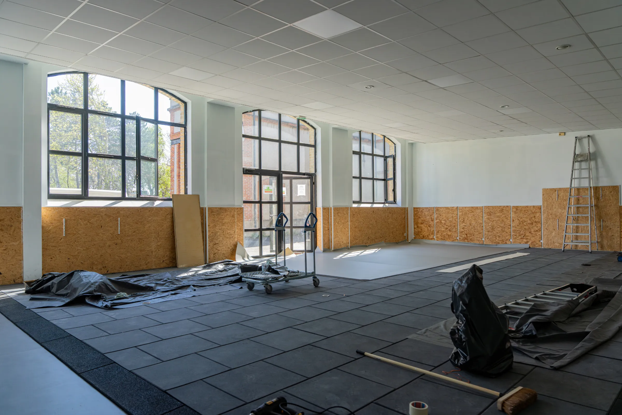 Commercial remodeling in Los Angeles with open interior build-out, unfinished flooring, large windows, tools, ladder, and renovation materials for a business space