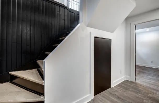 Condo remodeling in Los Angeles with staircase wall upgrade, dark accent paneling, updated flooring, interior trim, and modern hallway renovation