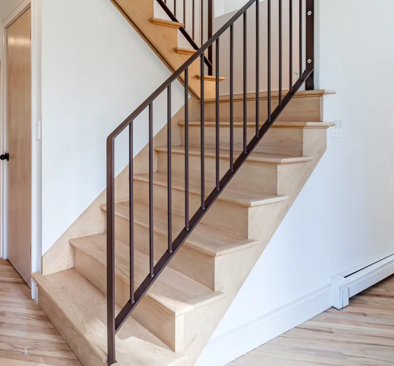 Condo remodeling in Los Angeles with wood staircase update, dark metal railing, hardwood flooring, and clean modern interior finishes