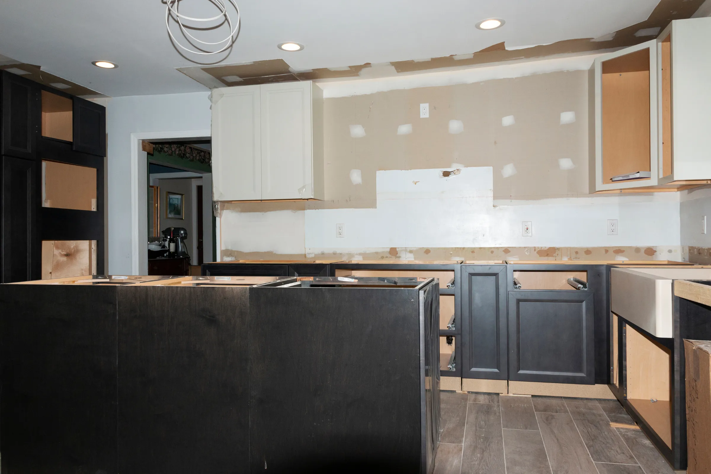 Kitchen remodeling in Los Angeles with cabinet installation, drywall repairs, unfinished backsplash area, recessed lighting, and renovation work in progress