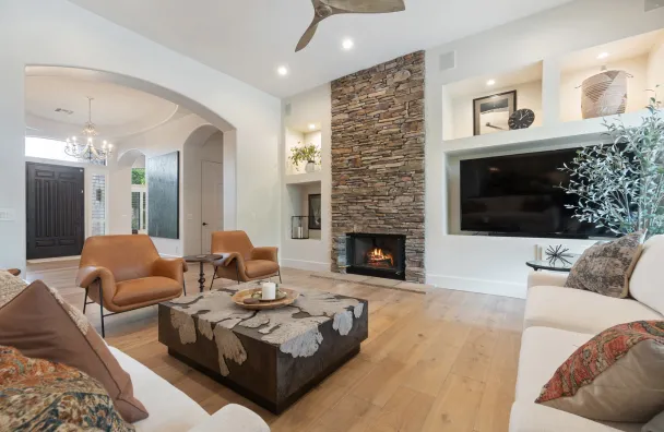 Luxury home remodeling in Los Angeles with upgraded living room, stone fireplace, built-in wall niches, hardwood flooring, recessed lighting, and premium interior finishes