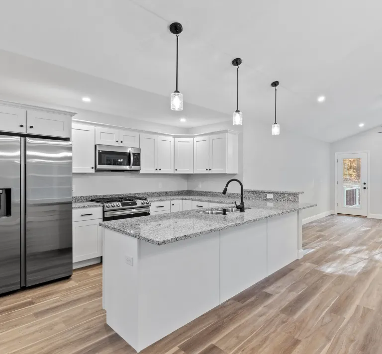 Luxury home remodeling in Los Angeles with premium kitchen upgrade, white cabinets, stone countertops, large island, pendant lighting, stainless steel appliances, and open interior flow